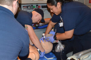 close up of male and female paramedics working on a manikin simulator