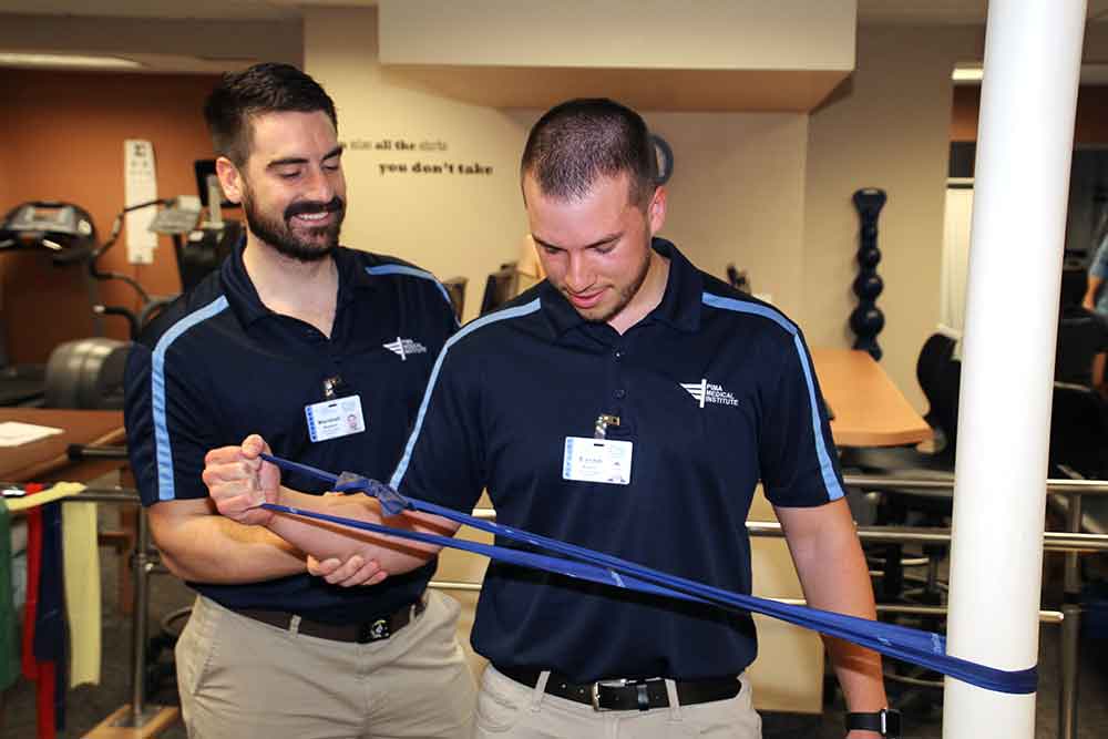 Physical Therapist Assistant students working on exercise movement with a band to help strengthen the arm.
