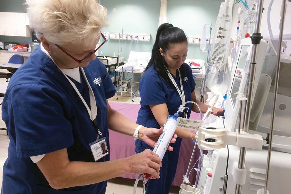 Two patient care technician students work with dialysis machines