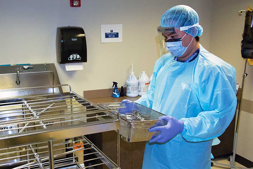 Suited_up_SPT_student_carrying_instruments_to_be_sterilized_in_lab_hero