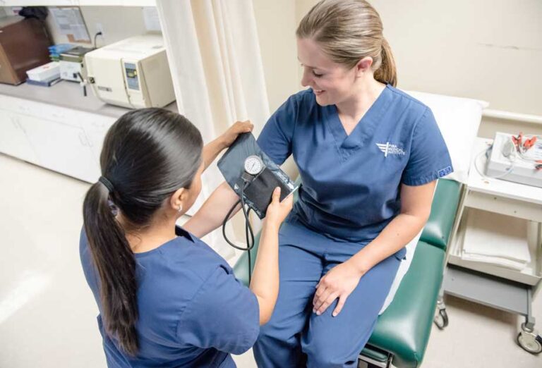 Medical assistant students practicing taking each other’s blood pressure in the lab classroom.
