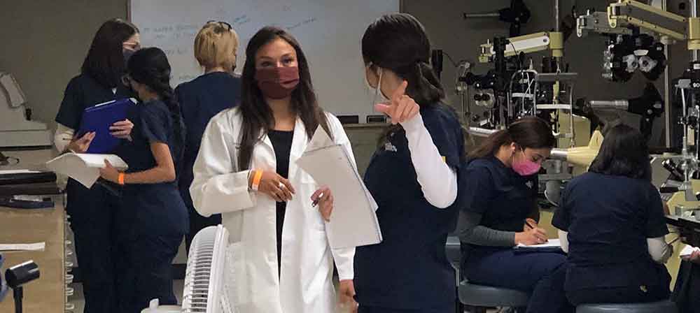 Woman talks to female student while in the ophthalmic medical technician lab classroom