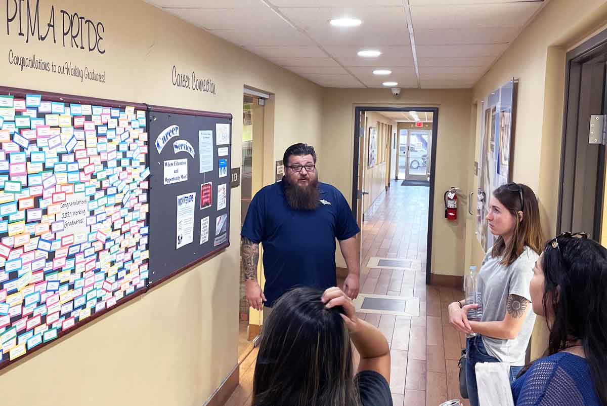 students and Mesa campus staff member stand in hallway during tour of campus
