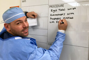 close up of nurse in PPE without a mask writing on a white board