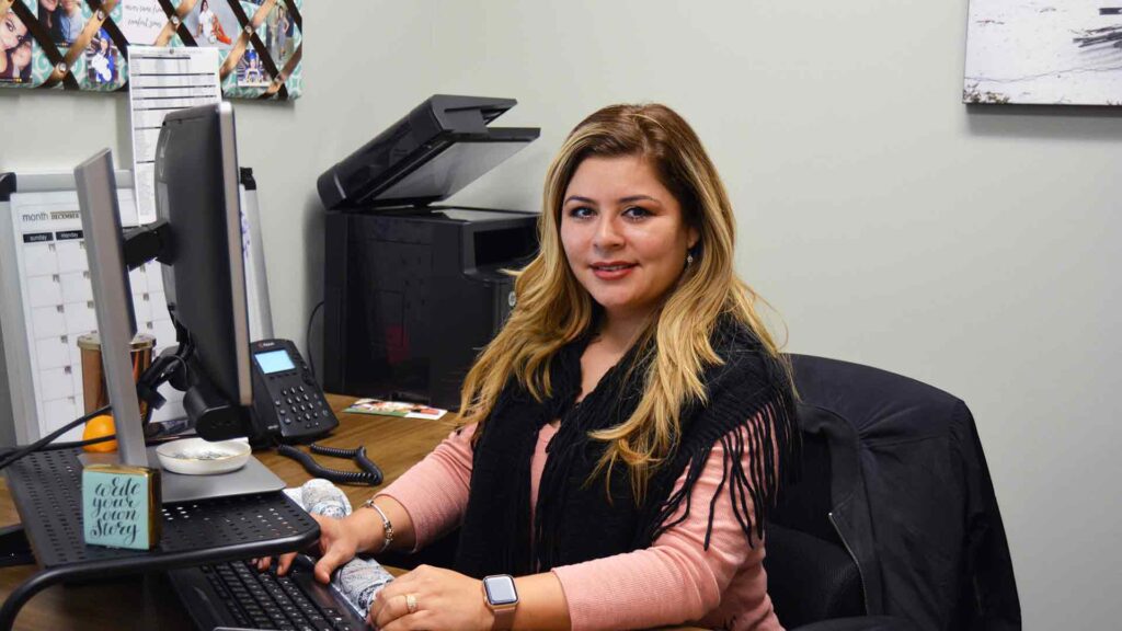 photo of Sandra Guevara doing work on a computer in her office