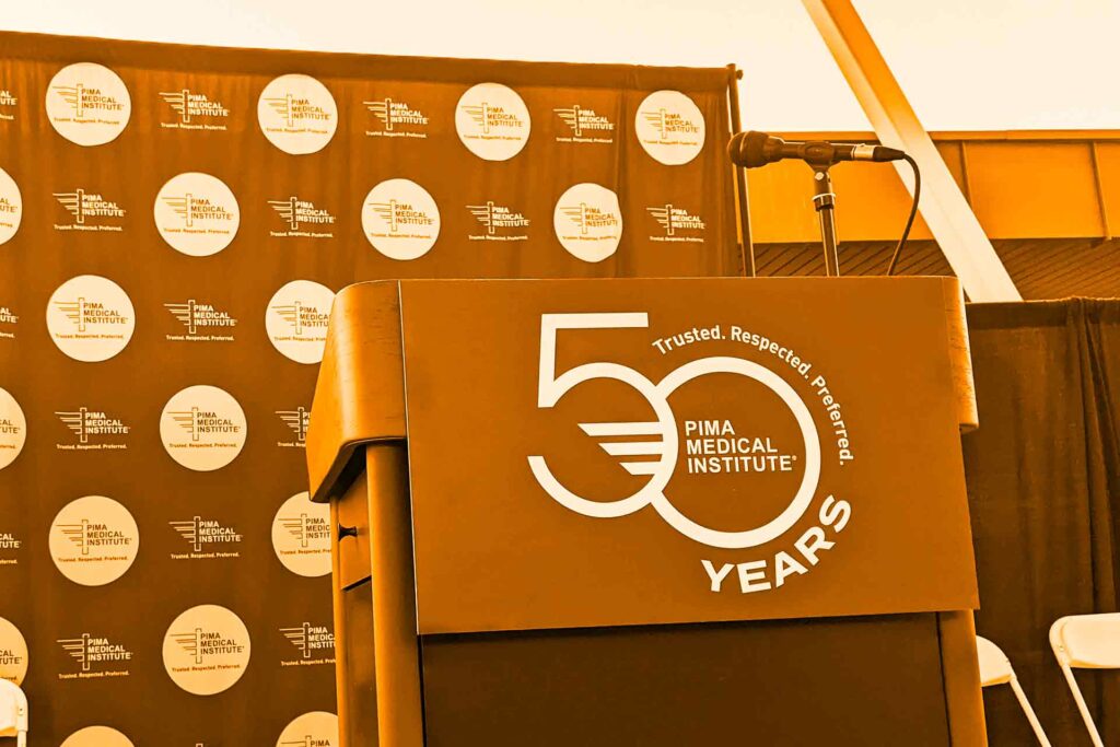 photo of stage podium with Pima Medical Institute 50th anniversary logo