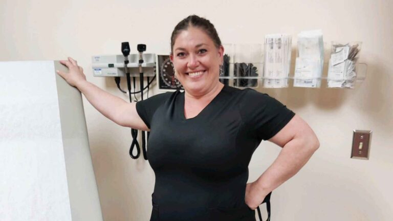 student, standing in scrubs posing for the camera.