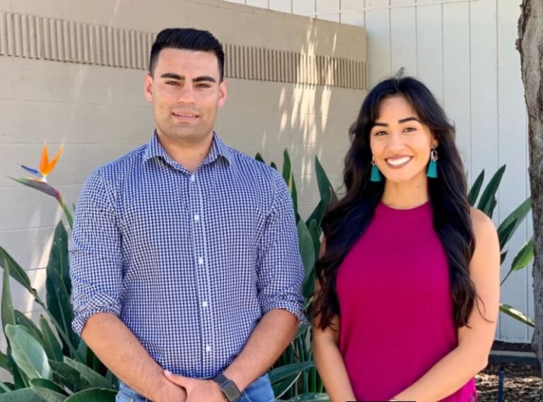 Male and Female stand smiling and facing the camera