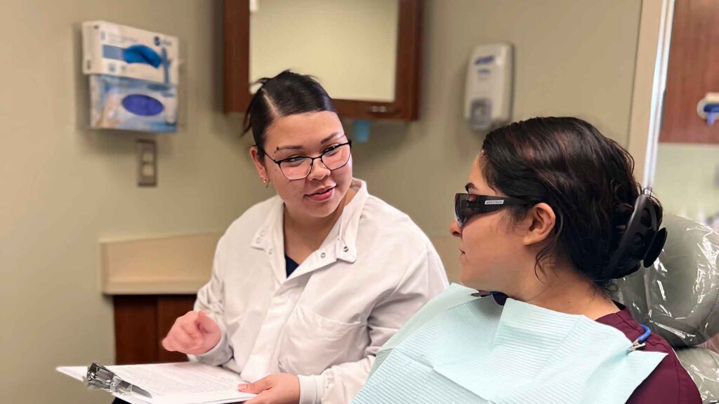 female dental assistant talks to dental patient during appointment