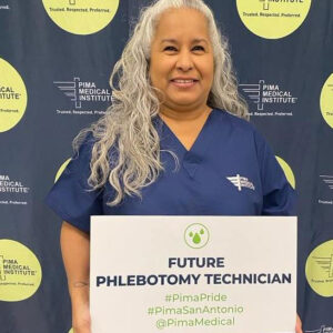 woman wearing Pima medical Scrubs holding a sign that reads “future phlebotomy technician”