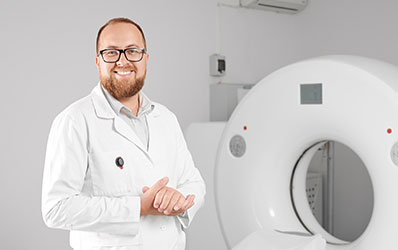 photo of a technologist standing in front of a CT machine