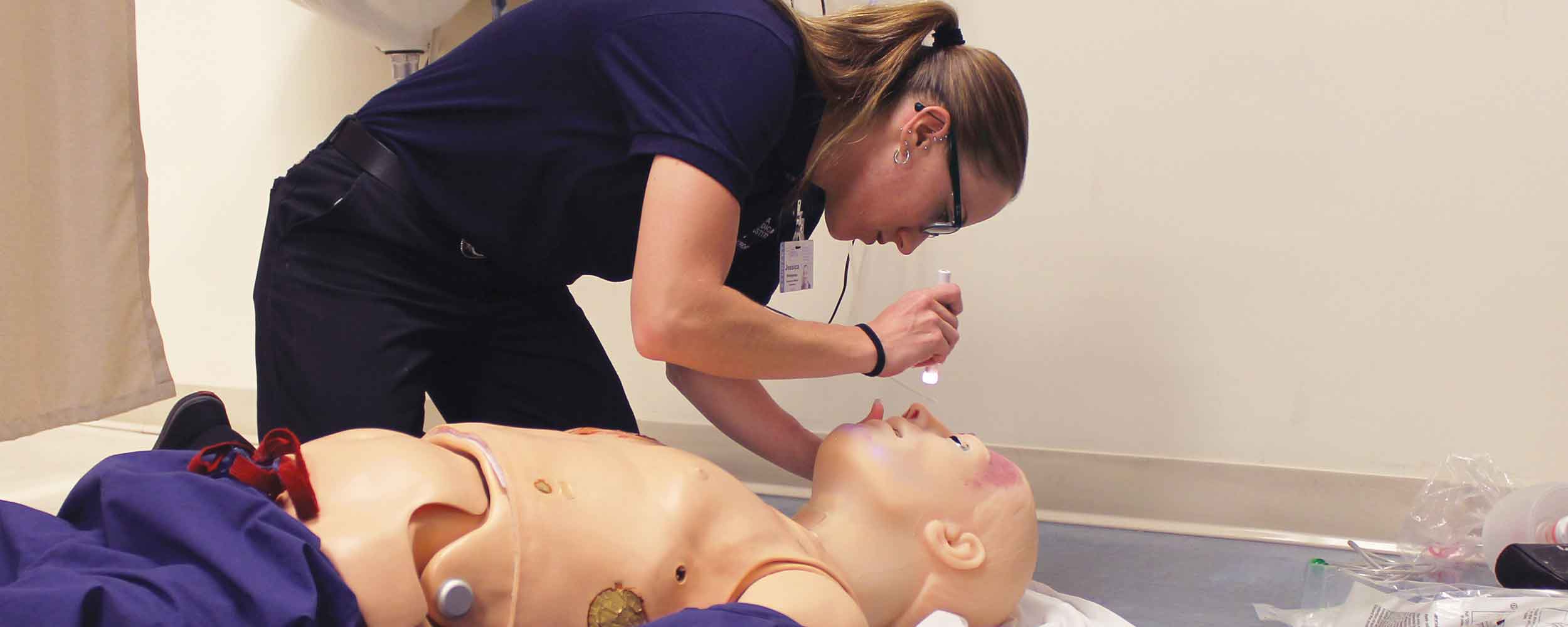 photo of an Emergency Medical Technician student examining a simulated patient