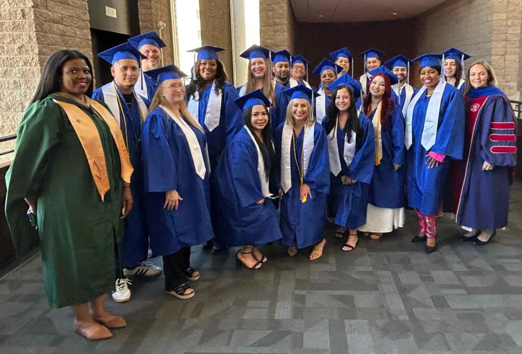 male and female graduates in caps and gowns pose in a group for a picture before the graduation ceremony.