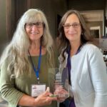 Two women posing with award at a national conference